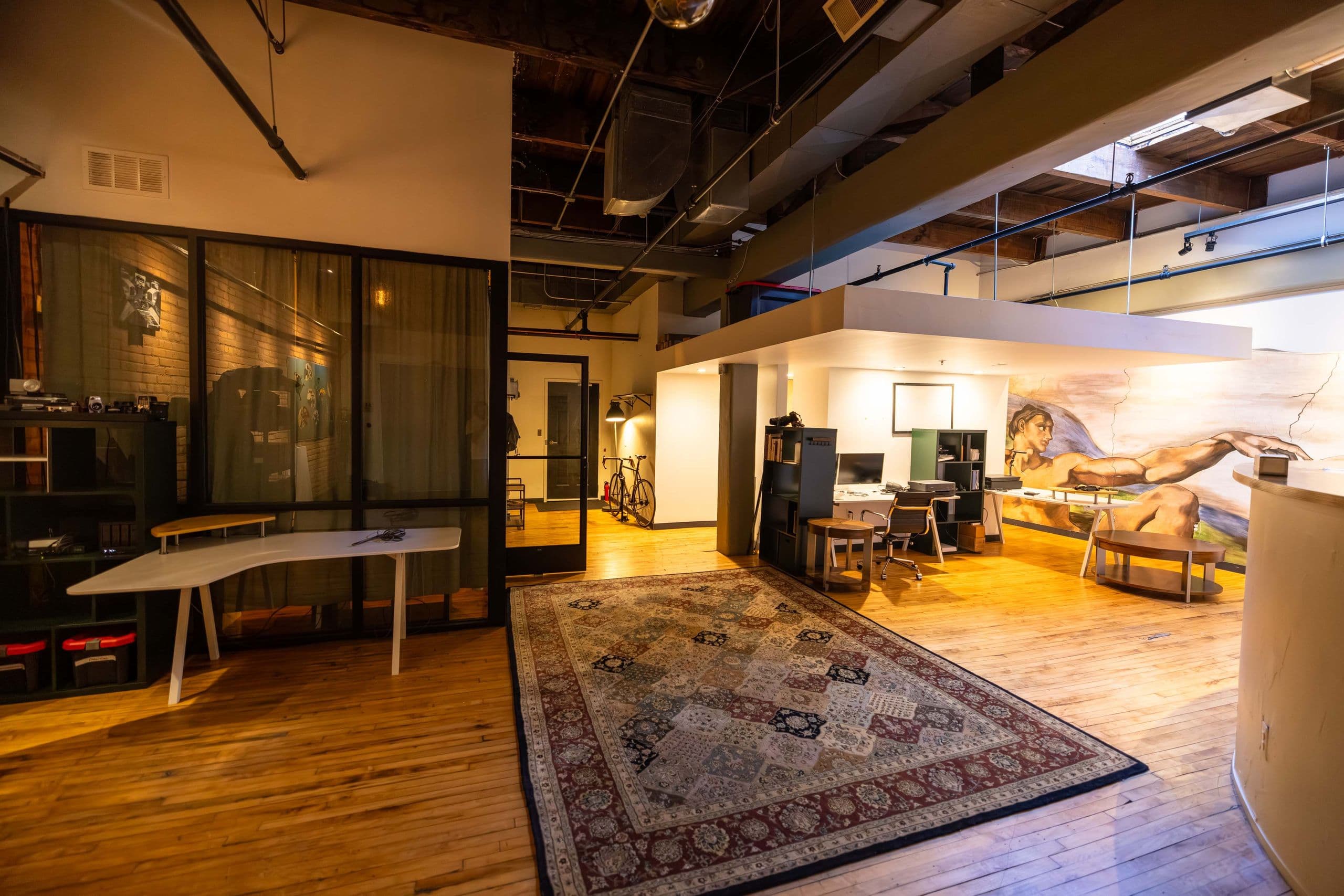 The 6th-floor Clubhouse loft: member desks, a mezzanine, and the mural wall